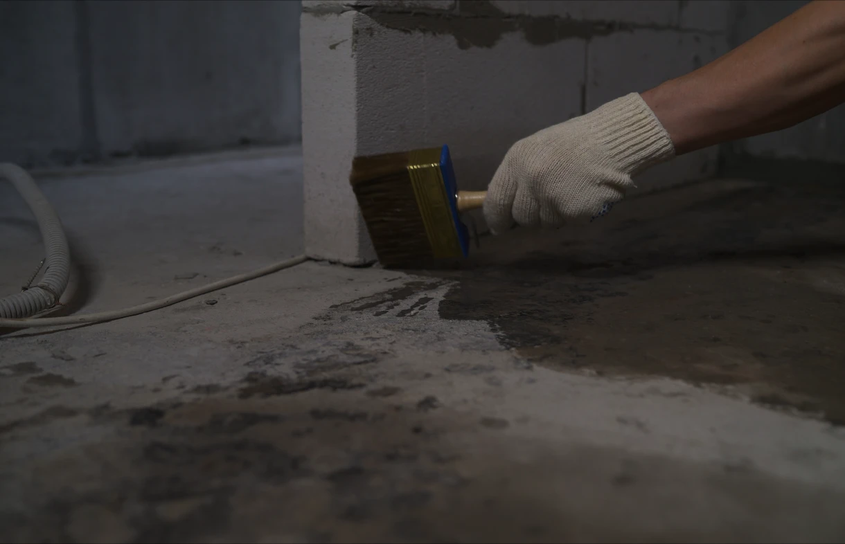 Person sealing concrete floor with a brush